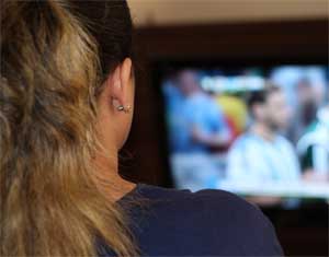 Woman Watching TV while working out in home gym on rowing machine